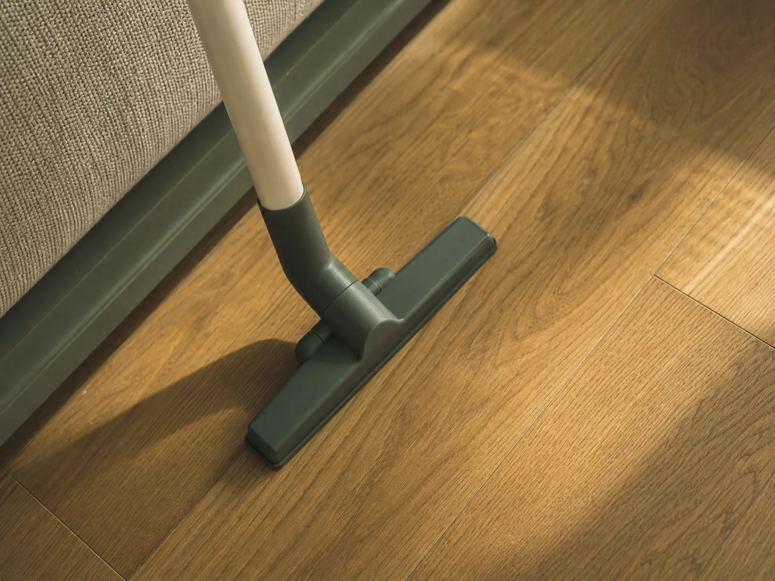 Overhead view of a narrow vacuum floor head next to an uncovered stretch of hardwood floor