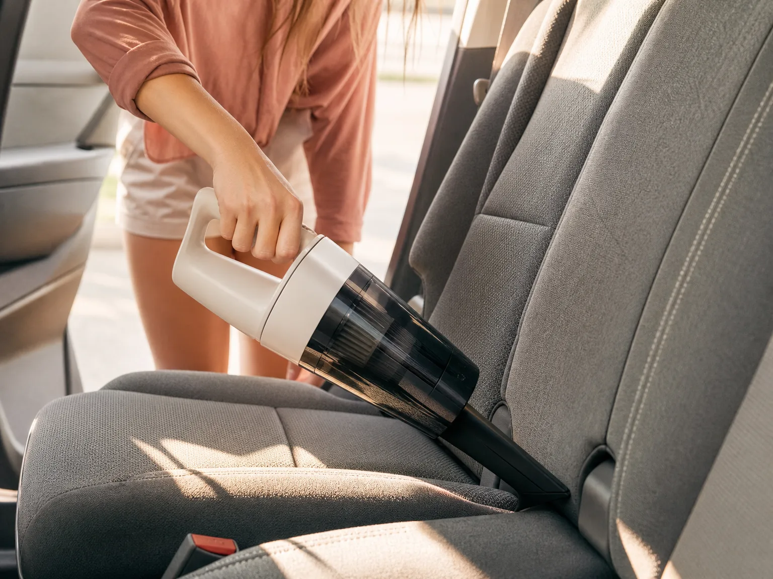Hand converting a cordless stick vacuum into a handheld unit to clean a fabric car seat