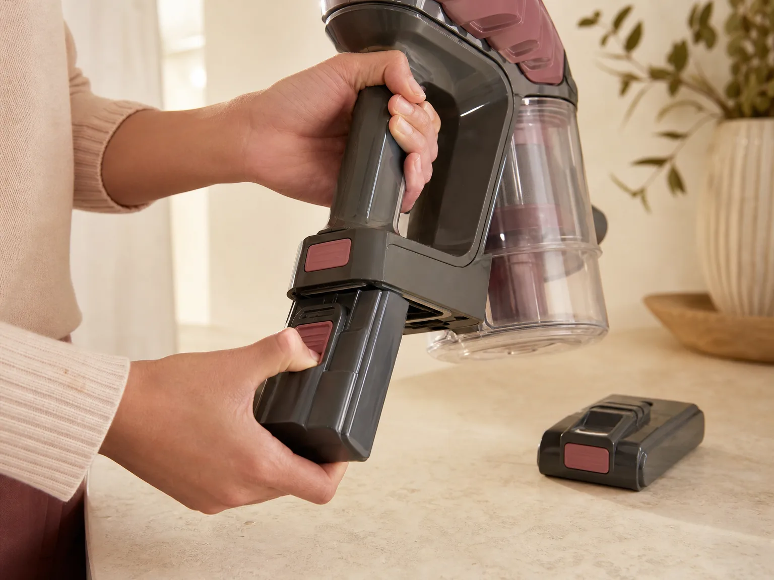Close-up of the detachable battery pack sliding out of the Eureka ReactiClean 410 handle mid-clean