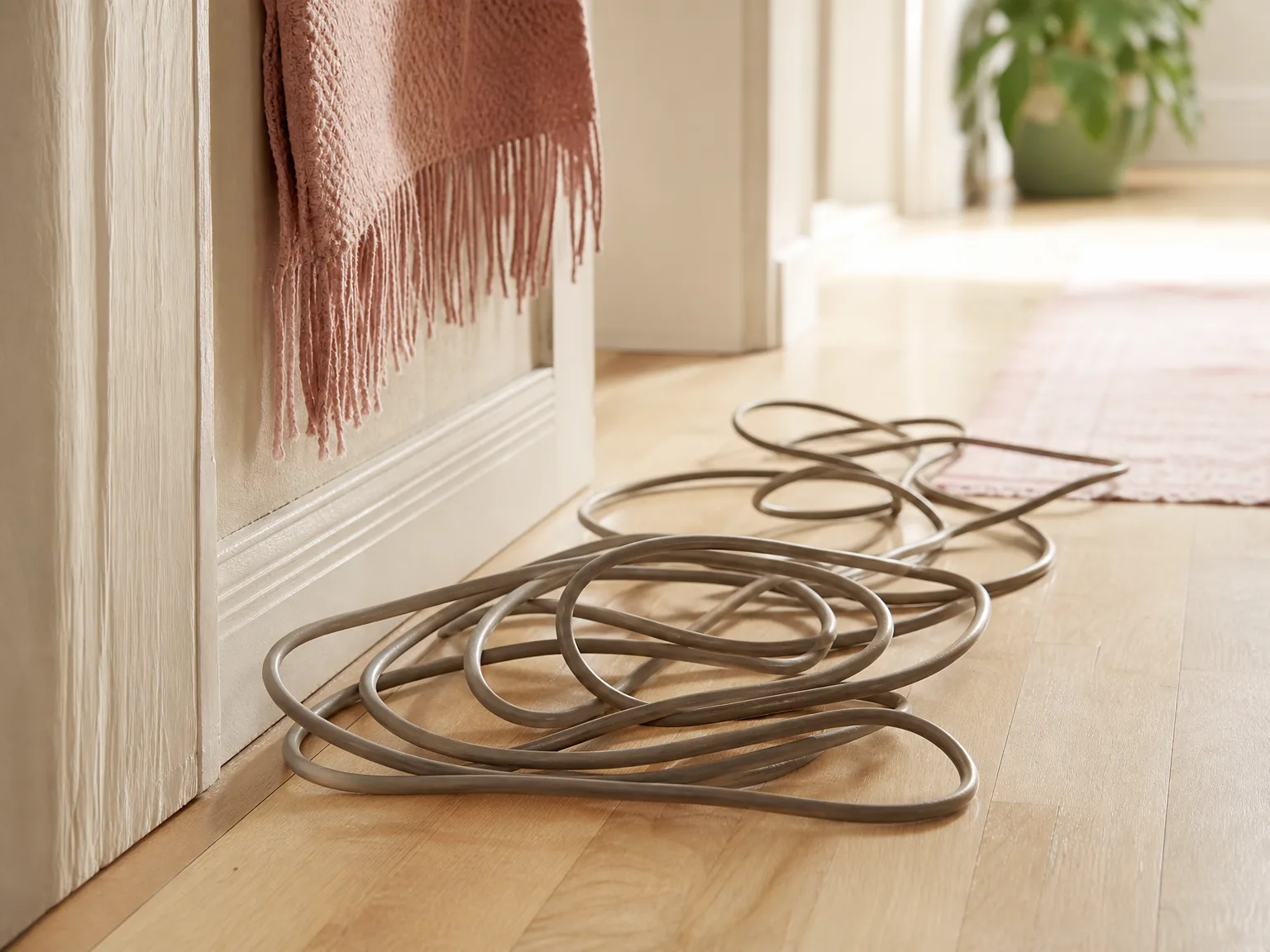 Close-up of a long vacuum power cord bunched on a hardwood hallway floor
